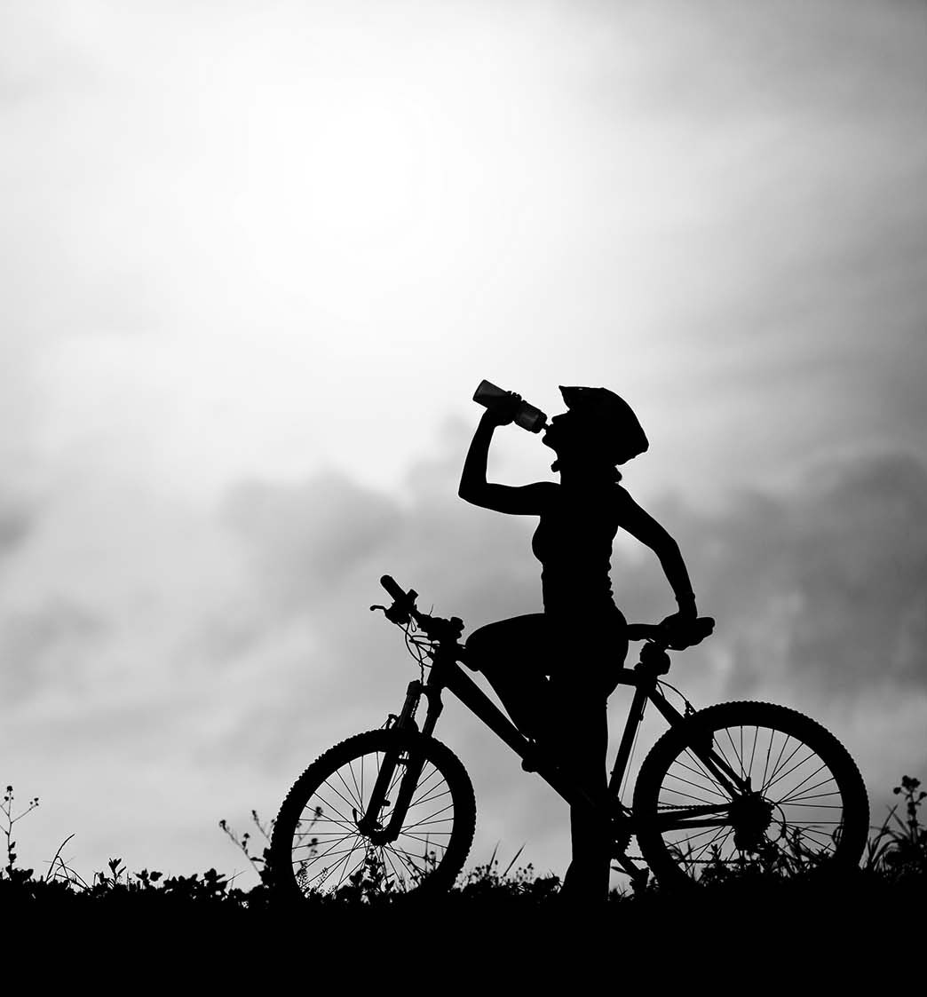 Black and white photo of a female on a bicycle refreshing
